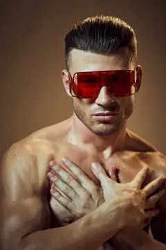 Крупным планом спортивный мужчина в модных очках, с накачанным мускулистым телом и стильной причёской