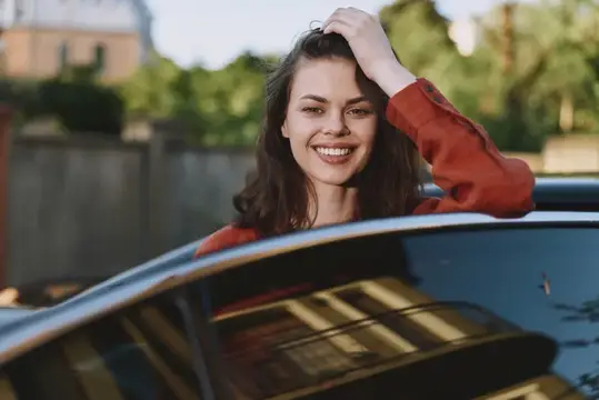 Улыбающаяся темноволосая девушка выглядывает из люка автомобиля
