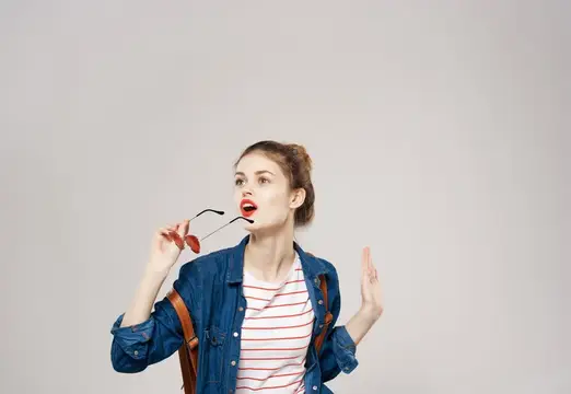 Улыбающаяся молодая женщина в модной одежде с рюкзаком, студентка колледжа