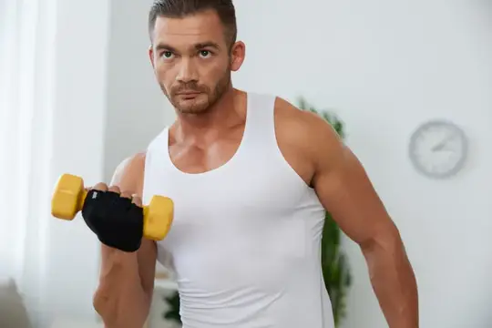 Спортивный мужчина с гантелью в белой майке дома