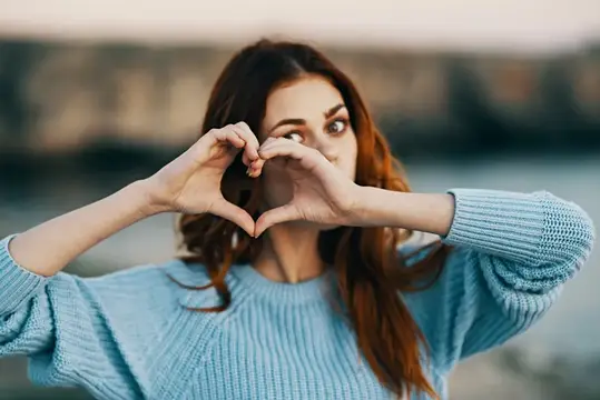 Женщина жестикулирует руками на природе, ощущая свободу, радость и свежий воздух