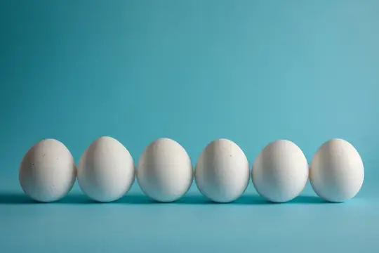 Шесть белых яиц в ряд на бирюзовом фоне