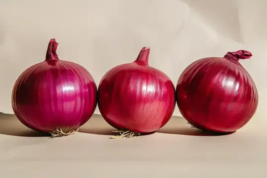 Три красные луковицы лежат рядом на светлом фоне