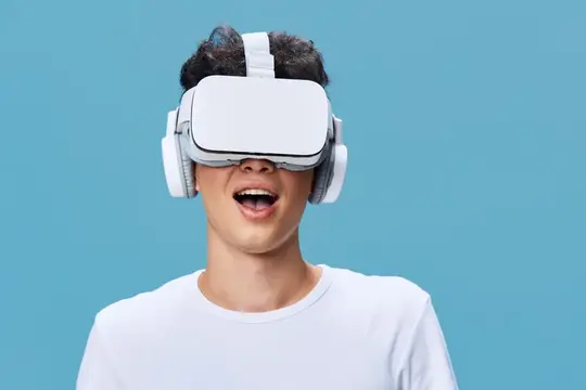 Улыбающийся парень в VR-очках и наушниках на голубом фоне