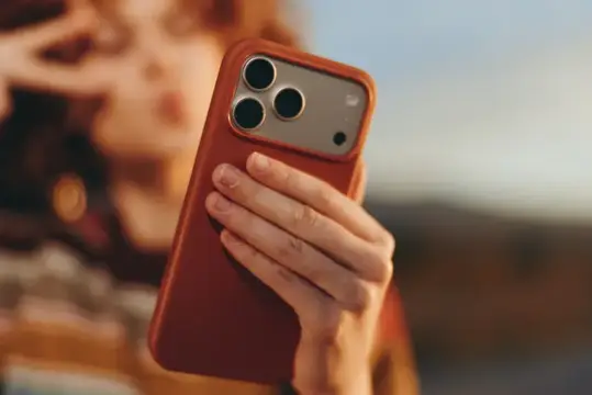 Женщина держит смартфон в терракотовом чехле на закате