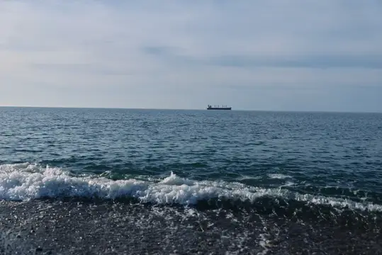 Одинокий грузовой корабль на горизонте спокойного моря