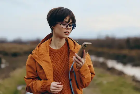 Молодая женщина в очках с телефоном на осенней прогулке