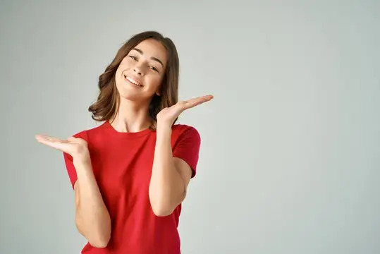 Улыбающаяся девушка в красной футболке показывает руками в стороны