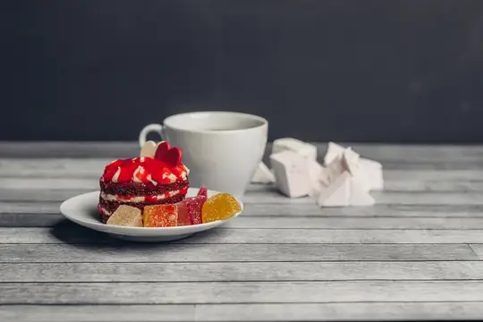 Красный десерт с мармеладом и белая чашка на сером столе