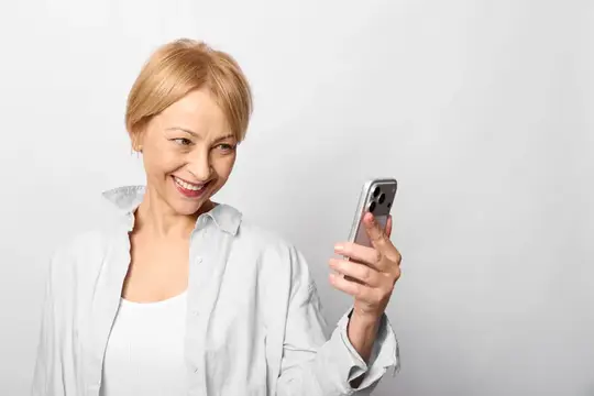 Пожилая женщина улыбается, глядя на экран смартфона