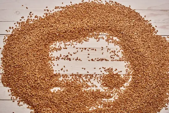 Сердечко из зерен пшеницы на светлых деревянных досках