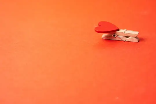 Деревянная прищепка с красным сердечком на оранжевом фоне