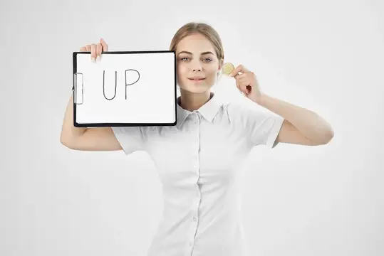 Молодая женщина держит планшет с надписью UP и монету