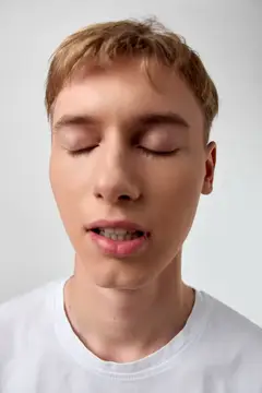 Выражение безмятежности с закрытыми глазами, гладкая кожа, нейтральный фон, мягкое освещение