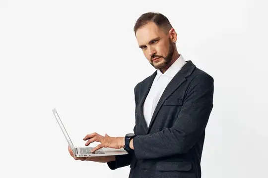 Серьёзный мужчина в пиджаке работает за ноутбуком на белом фоне