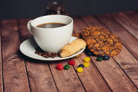 На кухонном столе лежит печенье, рядом стоит чашка с напитком
