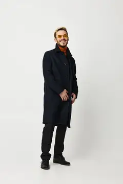 Улыбающийся блондин в тёмном пальто и жёлтых очках