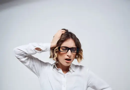 Деловая женщина в очках с документами, выражающая эмоции в офисе