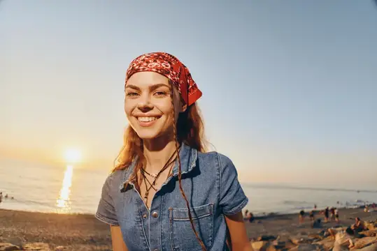 Улыбающаяся девушка в красной бандане на закатном пляже