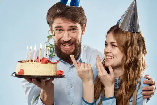 Бородатый мужчина и женщина в колпаках с тортом и свечами