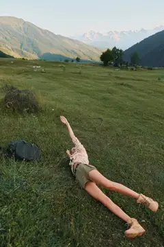Девушка лежит на траве на фоне гор и отдыхает