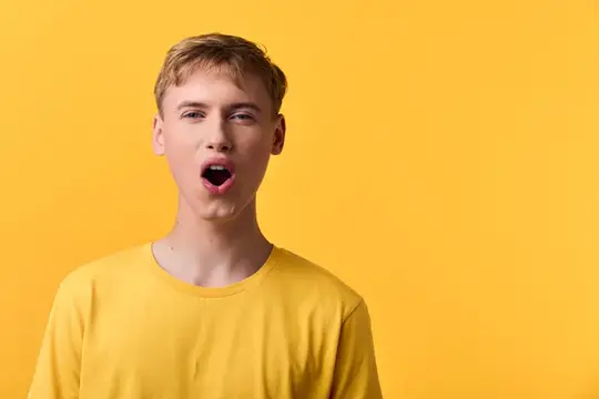 Удивлённый светловолосый парень в жёлтой футболке на жёлтом фоне