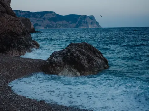 Большой камень на галечном пляже у моря в сумерках