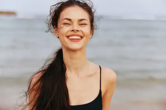 Улыбающаяся темноволосая девушка на фоне моря