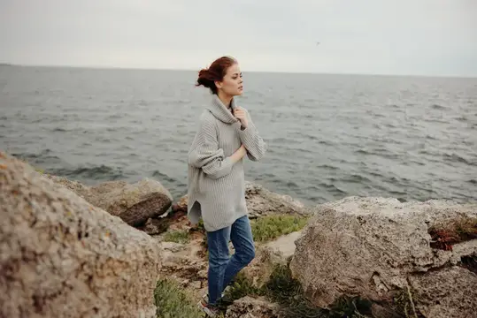 Симпатичная женщина в свитере любуется природой на фоне облачного моря