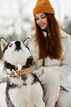 Молодая женщина гуляет зимой на свежем воздухе с хаски, наслаждаясь дружеским общением