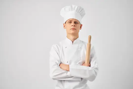 Мужчина в униформе шеф-повара на кухне, его профессия — работа на светлом фоне
