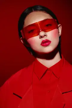 Азиатская девушка в красных очках и рубашке на красном фоне
