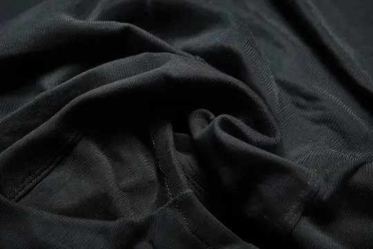 Черная ткань крупным планом с мягкими складками и строчкой