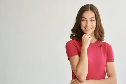 Весёлая женщина в красной футболке ухаживает за волосами на светлом фоне