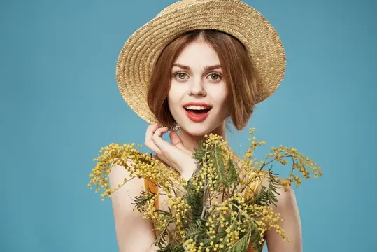 Улыбающаяся девушка в соломенной шляпе с ветками мимозы