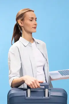 Молодая женщина с ноутбуком и чемоданом на голубом фоне