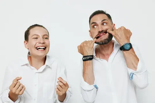 Мужчина корчит рожицы, а смеющаяся девушка смотрит на него