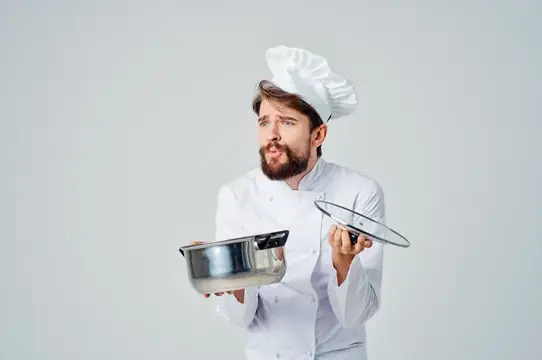 Мужчина в форме шеф-повара с кастрюлей в руках готовит еду для обслуживания