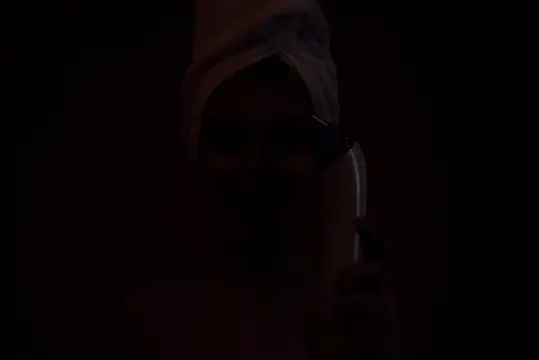 Мужчина в капюшоне говорит по телефону в полной темноте