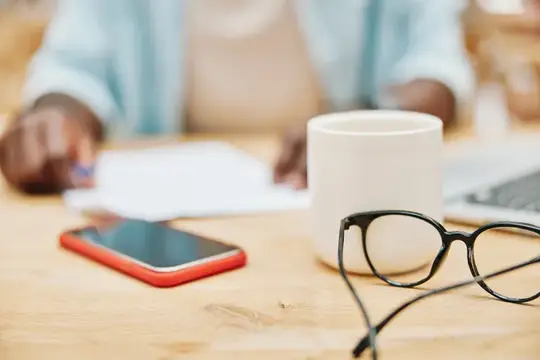 Очки, смартфон и кружка на столе во время работы