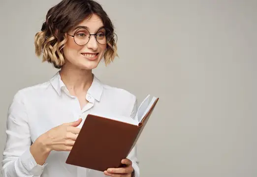 Улыбающаяся девушка в очках с книгой в руках