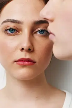 Молодая женщина с голубыми глазами и мужчина, шепчущий ей на ухо
