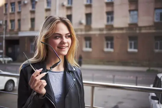 Модная женщина в кожаной куртке на открытом воздухе возле здания, блондинка, свежий воздух