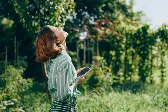 Яркая уличная сцена передает спокойствие, надежду и удивление, когда природа обрамляет расслабленный, задумчивый момент с мобильным устройством