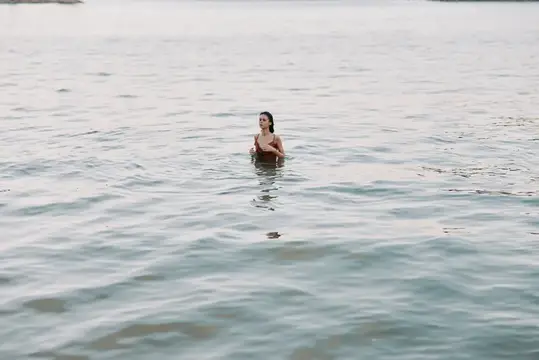 Молодая женщина купается в спокойном море в пасмурный день