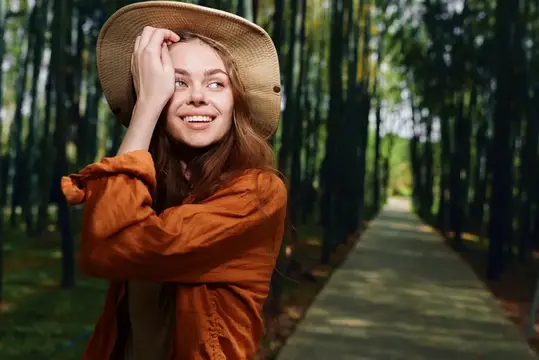 Улыбающаяся девушка в соломенной шляпе на лесной тропинке