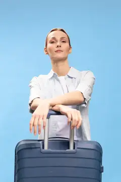 Молодая женщина с чемоданом на фоне голубого неба