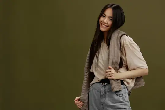 Улыбающаяся азиатская девушка в бежевой футболке на оливковом фоне
