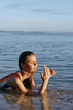 Молодая женщина с закрытыми глазами в воде на закате