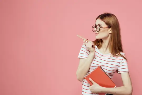 Красивая студентка держит книги, жестикулирует руками на розовом фоне